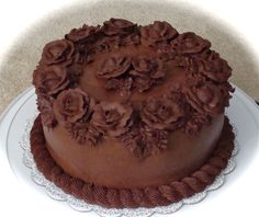 there is a chocolate cake with flowers on the top and bottom, sitting on a white plate