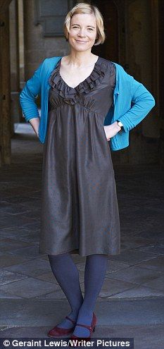 a woman standing with her hands on her hips wearing a black dress and blue cardigan