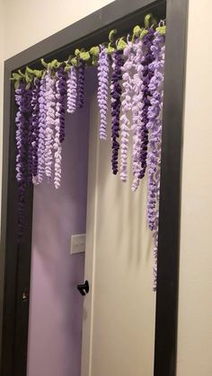 purple flowers hanging from the ceiling in front of a mirror