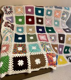 a crocheted granny blanket is displayed on a couch