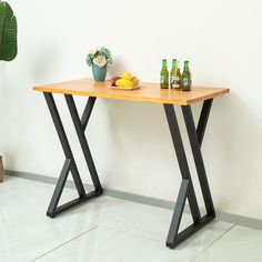 a wooden table with two bottles and some fruit on it next to a potted plant