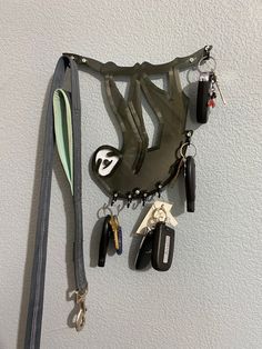 an assortment of car keys hanging on the wall next to a purse and keychain