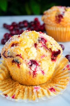 two cranberry muffins sitting on top of a white table next to some berries