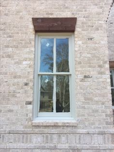 a cat sitting on the ledge of a brick building next to a window with glass panes