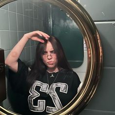 a woman with long hair standing in front of a mirror