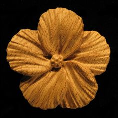 a piece of wood that has been carved into the shape of a flower on a black background