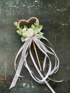 a heart shaped decoration with flowers and ribbons on the ground in front of an old wall