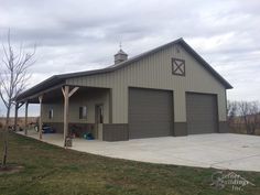 a two story garage with an attached carport and covered porch in the middle of a field