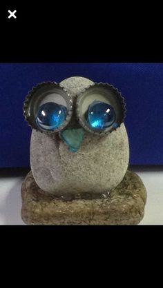 an owl figurine with blue eyes sitting on top of a stone slab in front of a blue wall