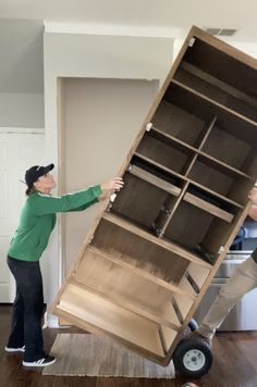 two people moving a bookcase on wheels