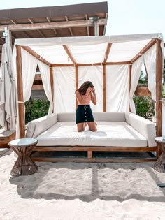 a woman standing in front of a bed on the beach