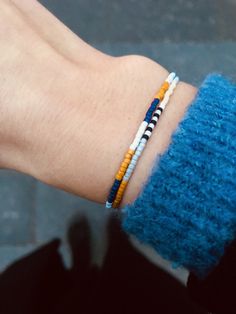 a person's hand wearing a bracelet with beads on it and a blue sweater