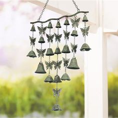 a wind chime with bells and butterflies hanging from it's side on a porch