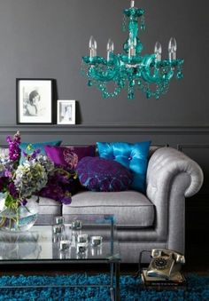 a living room with a couch, coffee table and chandelier in it's center