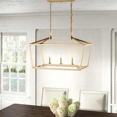 a chandelier hanging over a dining room table with flowers in the vase on it