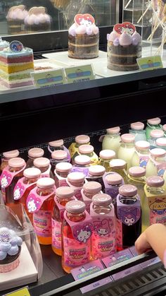 a display case filled with lots of different kinds of drinks and cakes on top of it