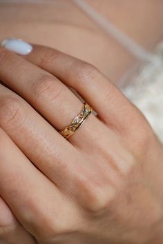 a woman's hand with a gold ring on her left hand and white nails