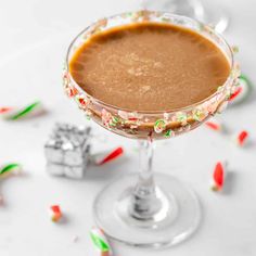 a close up of a drink in a glass with candy canes on the rim