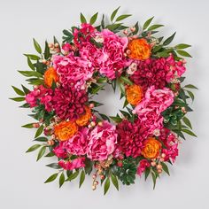 a wreath made up of pink and orange flowers on a white background with green leaves