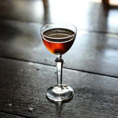 a glass filled with liquid sitting on top of a wooden table