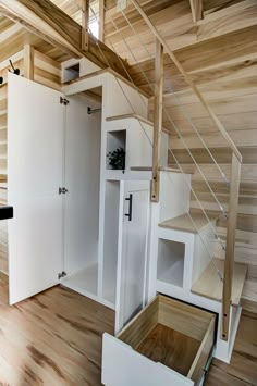 a room with wooden floors and white cabinets in the corner next to a stair case