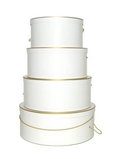 three white boxes stacked on top of each other with gold trimmings and rope