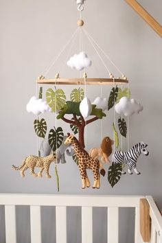 a baby crib with various stuffed animals hanging from it's sides and a mobile in the shape of a tree