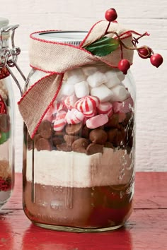 two jars filled with candy and marshmallows on top of a wooden table