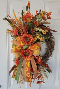 a wreath with orange and yellow flowers hanging on a door