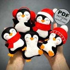 a hand holding six penguin finger puppets in red and white hats, scarfs, and mittens