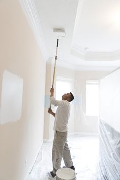 a man is painting the walls in an empty room