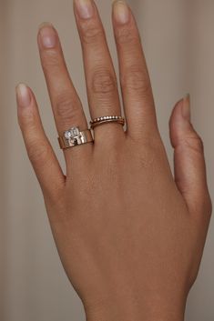 a woman's hand with two different rings on top of her ring and the middle finger