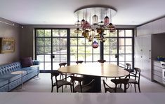 a dining room table with chairs and a couch in front of large windows that look out onto the backyard