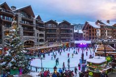 people are skating on an ice rink in front of a building with christmas trees and lights