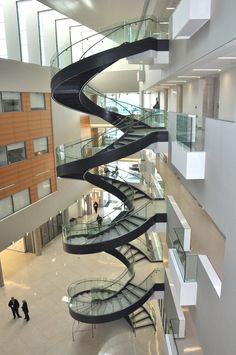 a spiral staircase in an office building with glass balconies