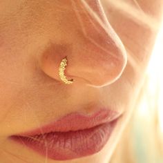 a close up of a woman's nose with a small gold moon piercing on it