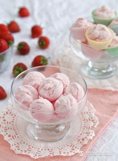 a glass bowl filled with pink ice cream next to strawberries