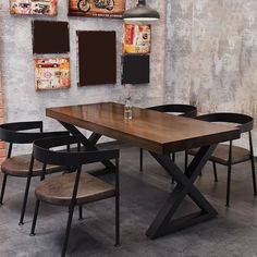 a wooden table with four chairs around it in front of a wall with pictures on it