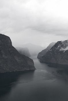 an aerial view of a body of water with mountains in the background on a cloudy day