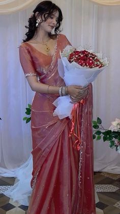 a woman in a red sari holding a bouquet of flowers