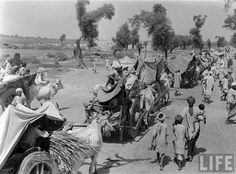 an old black and white photo of people walking down the street with tents in the background