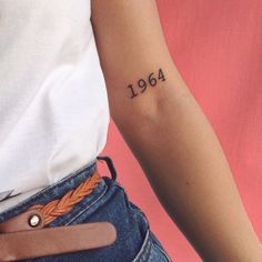 a woman's arm with a tattoo on it that reads, 1994 and has an orange braid around the wrist