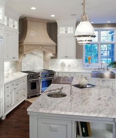 a large kitchen with white cabinets and marble counter tops, along with stainless steel appliances