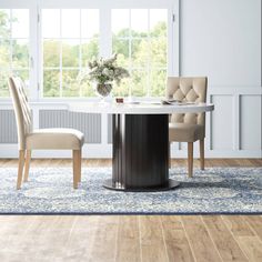 a dining room table with two chairs and a rug on the floor in front of it