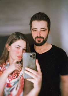 a man and woman taking a selfie in front of a mirror with their cell phone