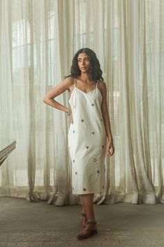 A dreamy and dainty slip dress. Embellished with traditional Lambani hand embroidery from Karnataka, this piece has been meticulously crafted with hand woven organic cotton, naturally dyed cotton embroidery threads and lush mirror work. Rich and contemporary in form yet purposefully rooted in textile heritage of the local Banjaras, each piece reflects the warmth, simplicity and craft of these women who have made us fall in love with Lambani. Slow down and take a moment to savour the piece and th Bohemian Cotton Embroidered Dress For Festive Occasions, White Dresses With Mirror Work For Summer, Traditional Spring Dress With Mirror Work, Traditional Dress With Mirror Work For Spring, Summer Festive Cotton Embroidered Dress, Cotton Embroidered Dress With Woven Motifs For Summer, Festive Summer Embroidered Cotton Dress, Folk Style Embroidered Dress With Woven Motifs For Summer, White Bohemian Dress With Mirror Work