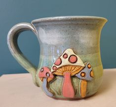 a ceramic mug with mushrooms painted on the outside and inside, sitting on a table