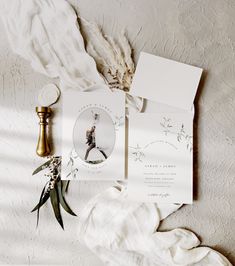 the wedding stationery is laid out on top of an unmade bed with white sheets