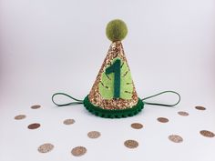 a green and gold birthday hat sitting on top of a white table covered in confetti