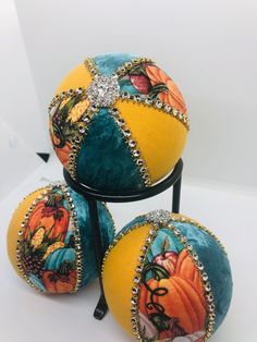 three orange and blue decorated balls sitting on top of a black metal stand next to each other